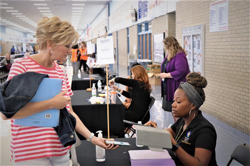 Shaune Ferguson with the Talent Acquisition teach checks in a new teacher.